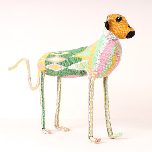 A handmade beaded baboon sculpture, featuring a multicolor patterned body, a tan head, and long thin legs, photographed against a plain light background.