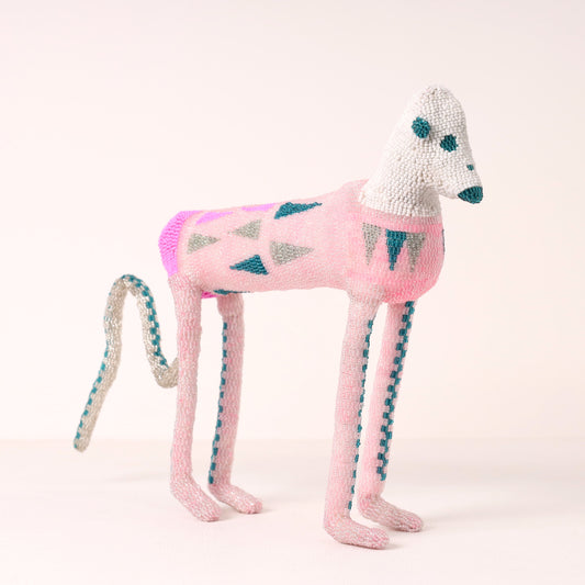 A handmade beaded baboon sculpture in pink, white, and teal, photographed against a clean, light off-white background.