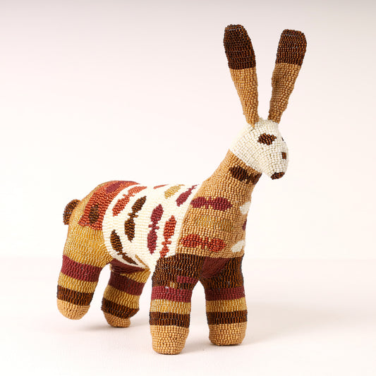 A handmade, beaded rabbit figurine in earthy brown, beige, and rust-red tones, set against a plain light background.