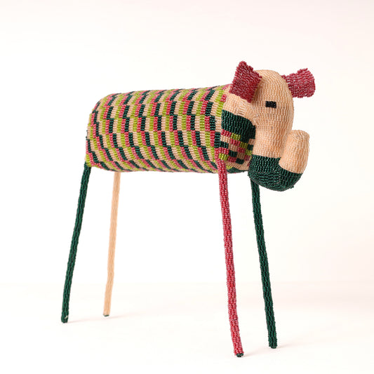 A handmade beaded elephant sculpture, featuring a striped body in green, pink, and beige, with a beige face, dark green muzzle, and long legs in green, pink, and beige, set against a plain white background.