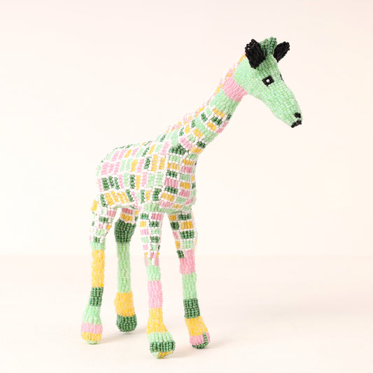 A handmade beaded giraffe sculpture in pastel colors of green, pink, yellow, and white, standing against a plain light background.
