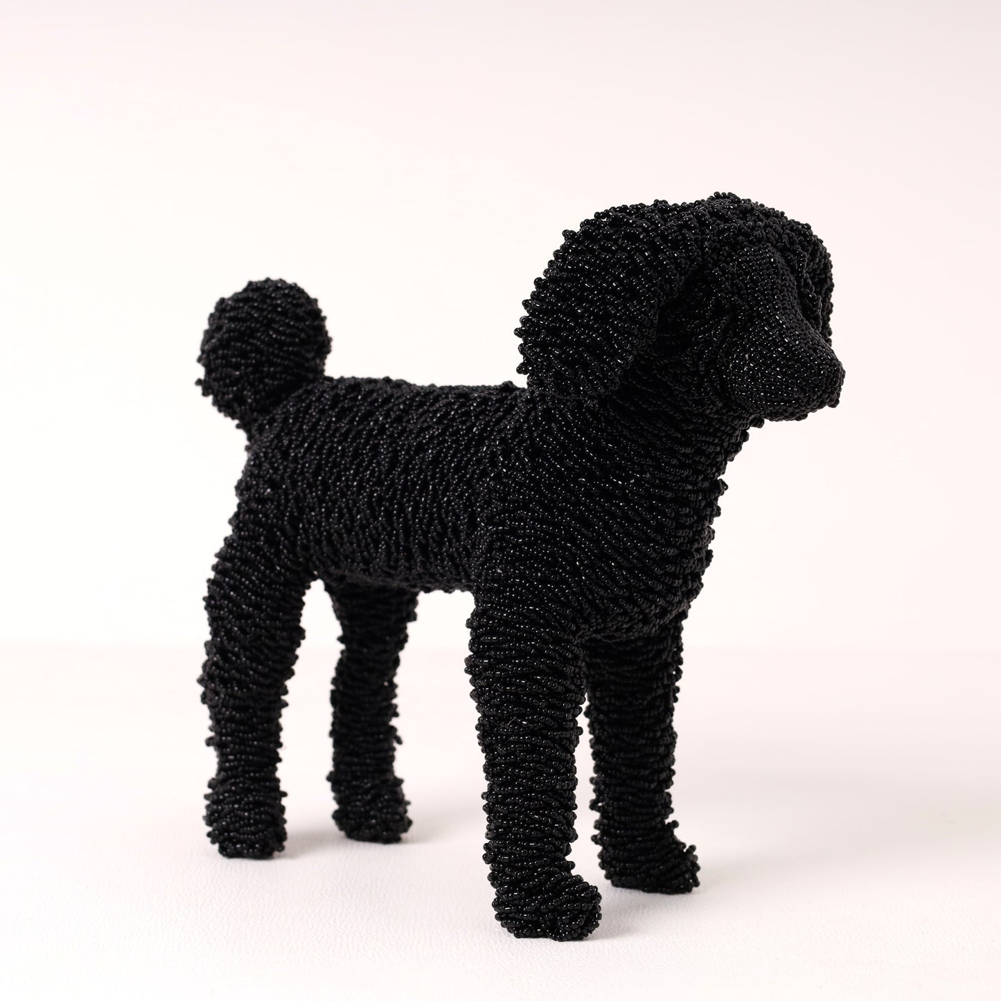 A black poodle-shaped decorative figurine made of beads, standing against a plain light background.