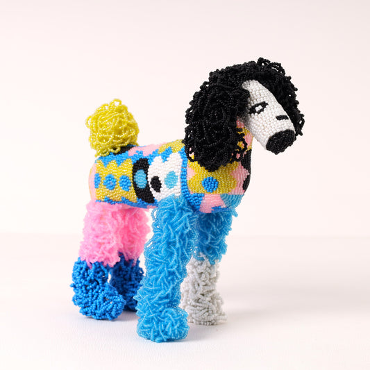 A colorful, handcrafted beaded poodle sculpture, featuring black curly fur, a yellow pom-pom tail, and a patterned body in pink, blue, yellow, and white.
